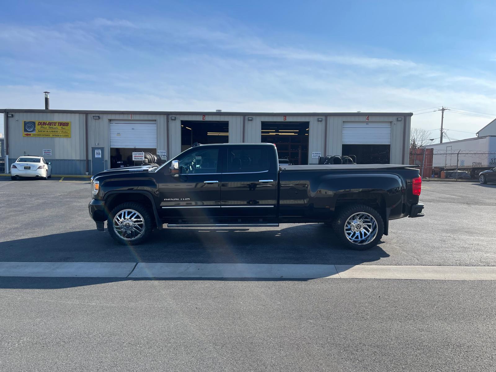 Black GMC Denali HD with chrome wheels at storefront